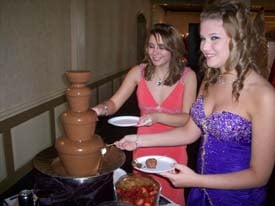 2 girls dipping their strawberries into the chocolate