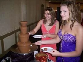 2 girls dipping their strawberries into the chocolate