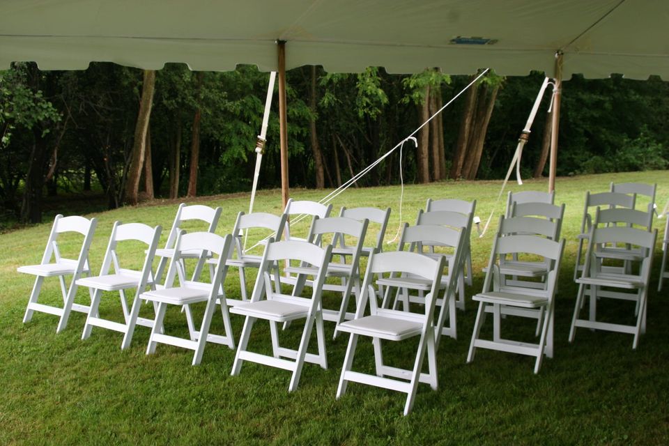 white padded wedding chairs lined up under white wedding tent to sit during ceremony 1